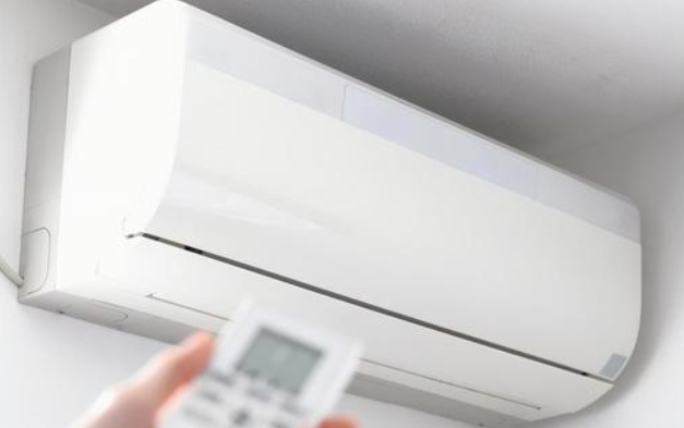 A sanitation worker wearing an orange uniform loads garbage onto a truck. Various carts and bags filled with waste materials like cardboard, plastic, and other refuse surround him. Several brooms are visible, indicating cleaning activities. In the background, people pass by and a telephone booth is visible.